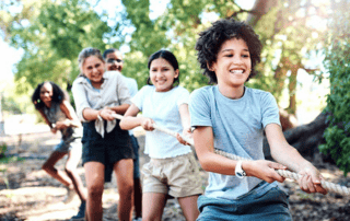 young children playing tug of war and smiling