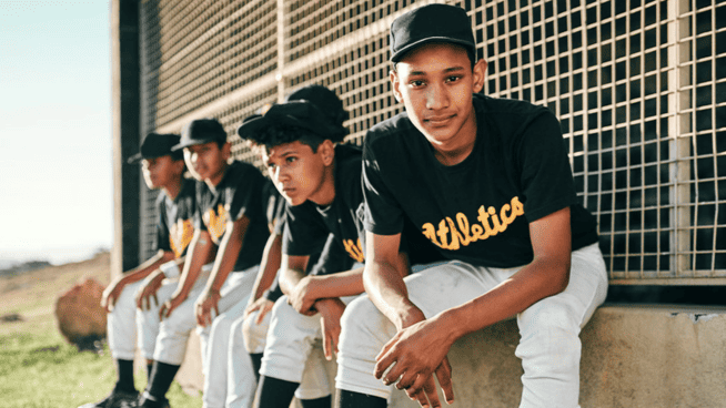 young male baseball players sitting on bench dealing with mental health