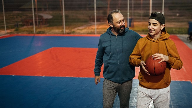 Dad with arm around son on a basketball court