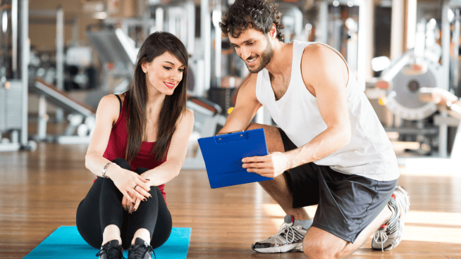 Youth female with male trainer during youth fitness training program at gym