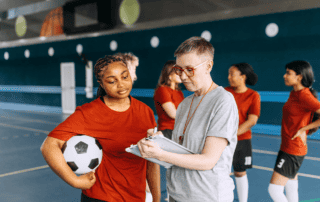 Female coach working with young female soccer player